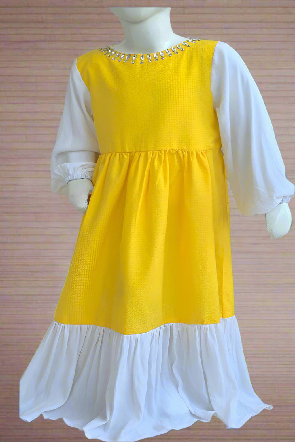 Mannequin wearing a yellow and white dress against a brick wall.