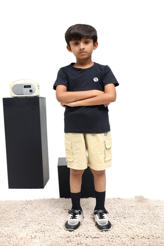 Child wearing a black t-shirt and beige shorts standing next to a black and white robot on a white background