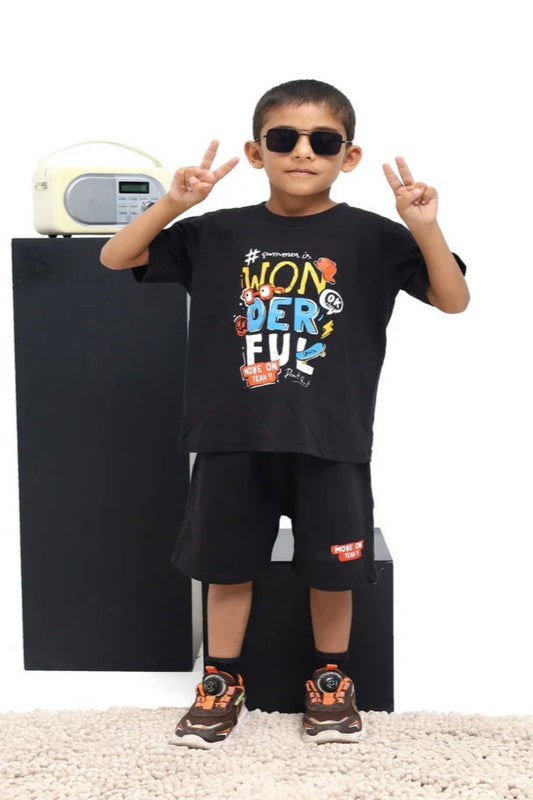 Child wearing a black t-shirt with colorful text and graphics, standing in front of a black appliance.