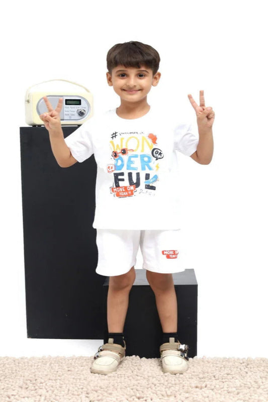 Child wearing a white t-shirt with colorful text and shorts, standing against a plain background