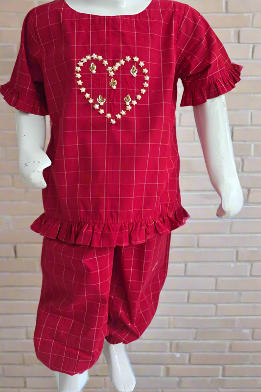 Red checkered outfit with heart design on a mannequin against a white brick wall.