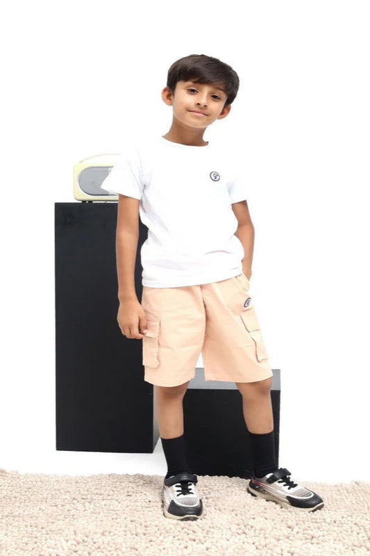 Young boy wearing a white t-shirt and beige shorts standing against a white background