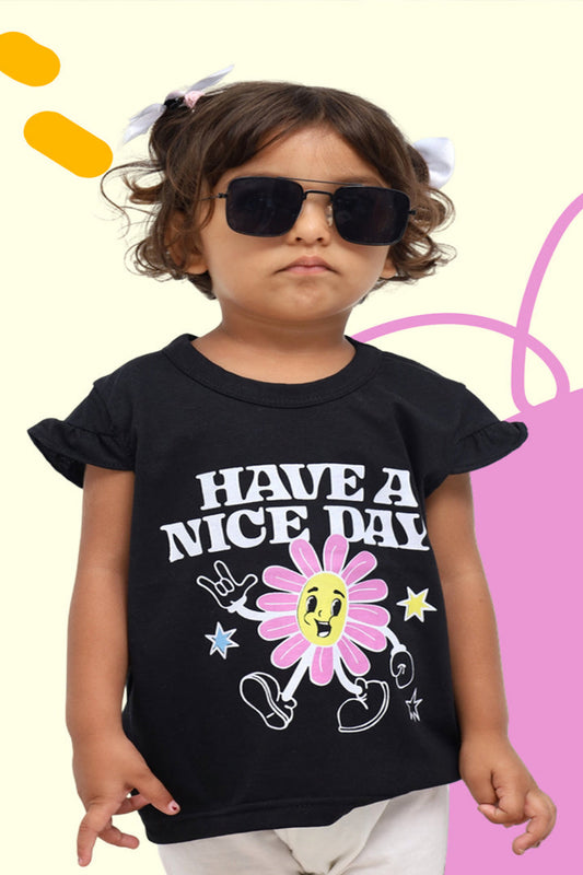 Child wearing a black t-shirt with a colorful graphic and text, standing against a multicolored background.