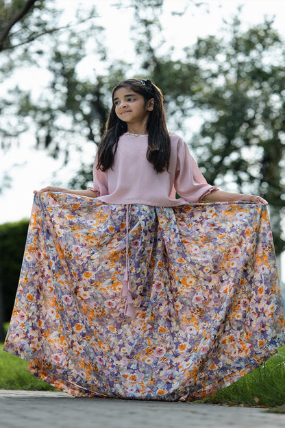 Young girl holding a floral skirt outdoors with trees in the background