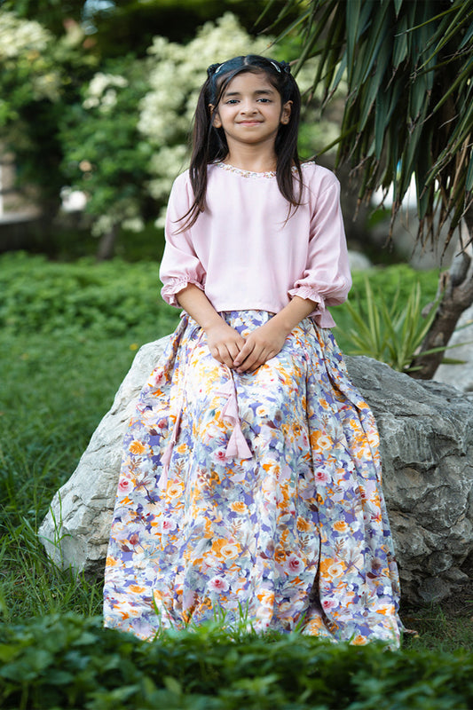 Young girl in a floral dress standing outdoors with greenery around