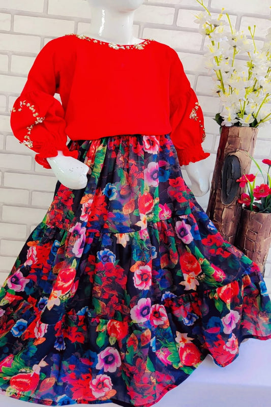 Red top with floral skirt on a mannequin against a white brick wall.